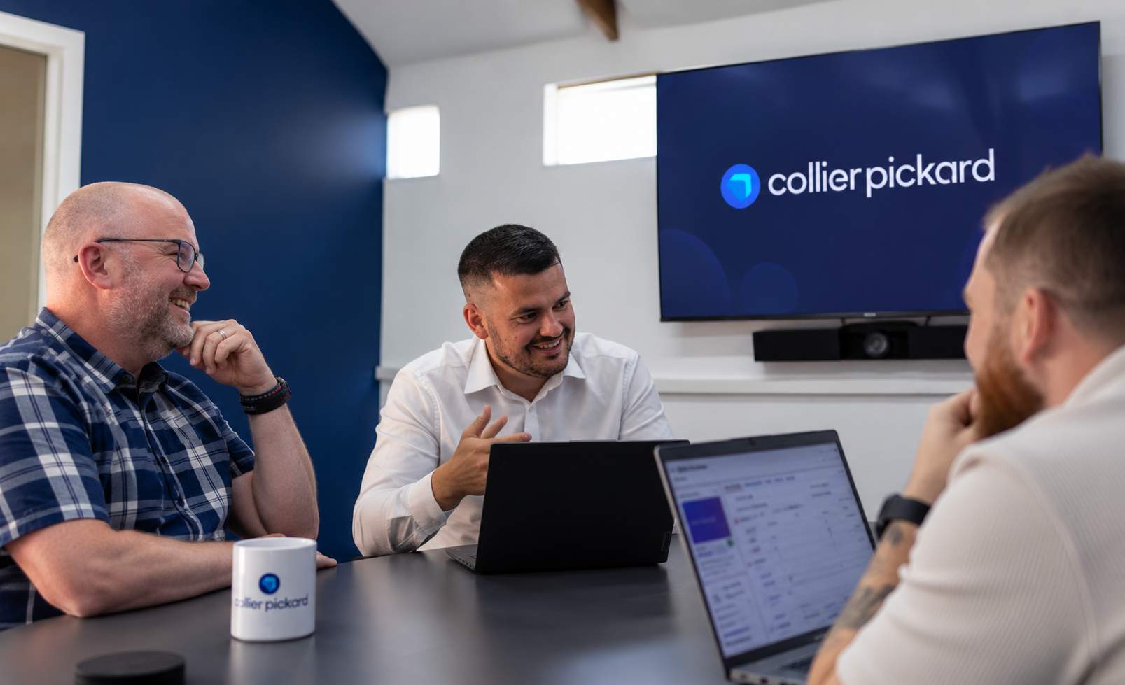 AI-recreated image of a photo in the Collier Pickard office of Laurie, Steve and Ollie around a table discussing Infor CRM SLX Upgrades.