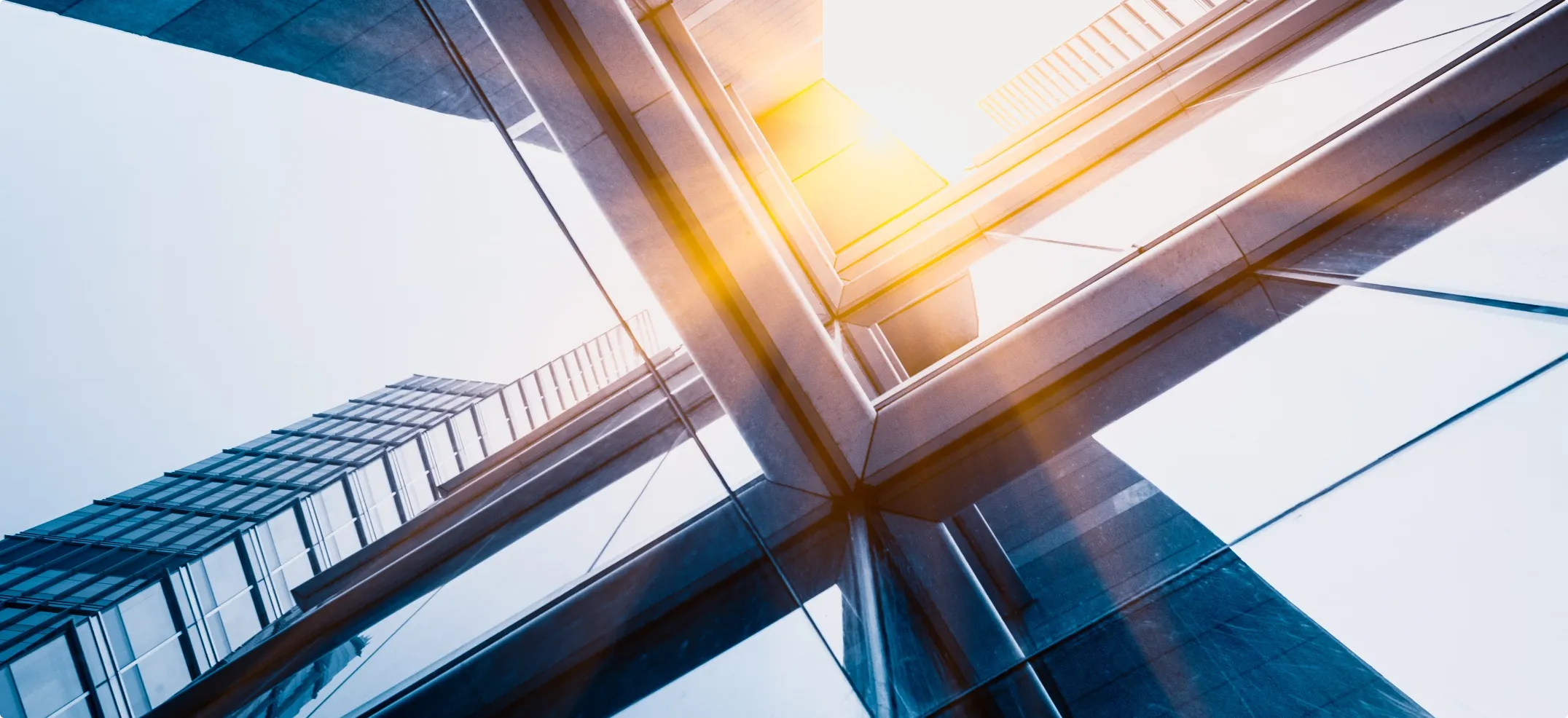 Image of a mostly glass building, camera pointing towards the glare of the sun