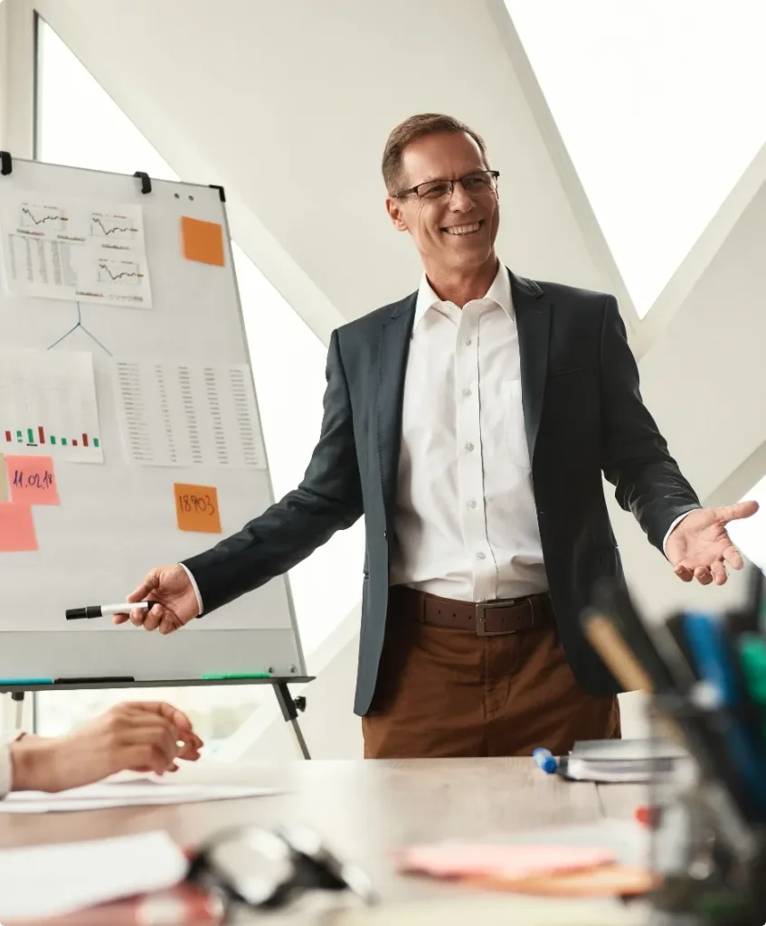 good results happy mature businessman formal wear standing near whiteboard smiling while working modern office business concept@2x