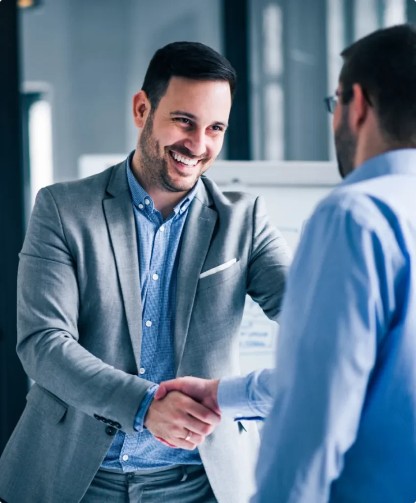 Two smiling businessmen shaking hands while standing office